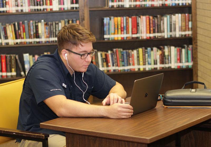 male student studying on a laptop at the library